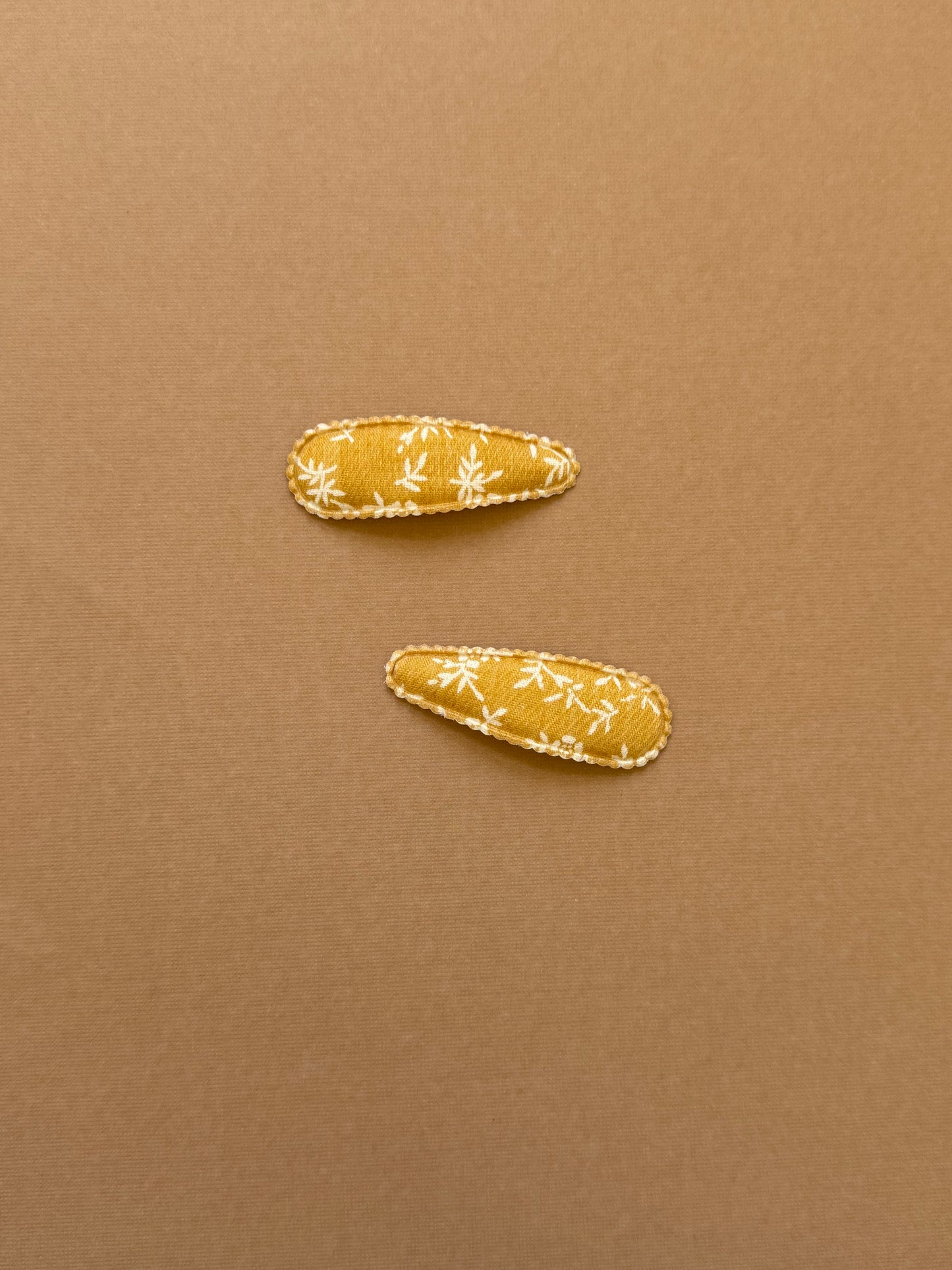 Mustard yellow snap clip with scalloped edge and white leaf print