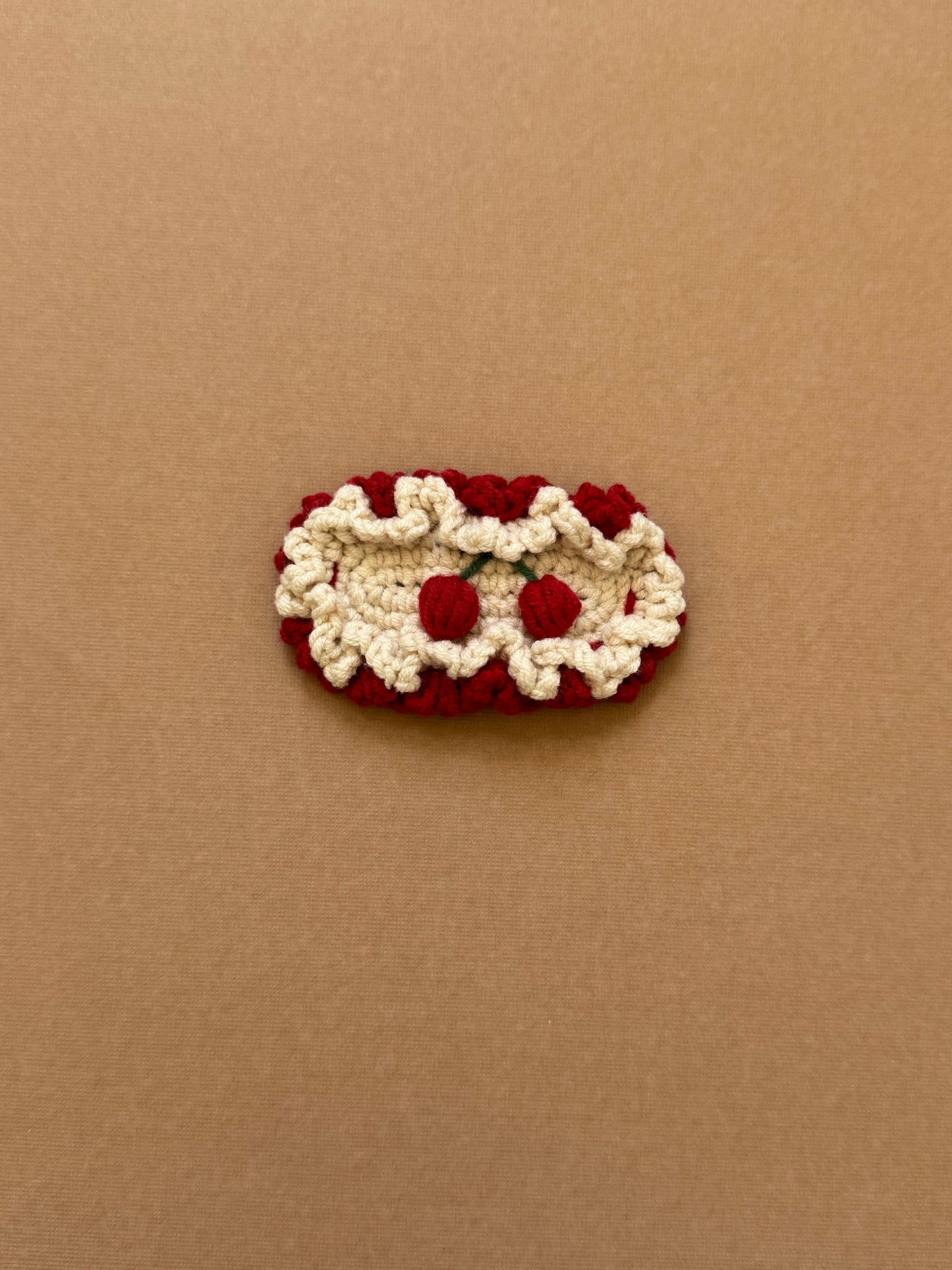 Hand-crocheted snap hair clip with cream scalloped edges and red embroidered cherries
