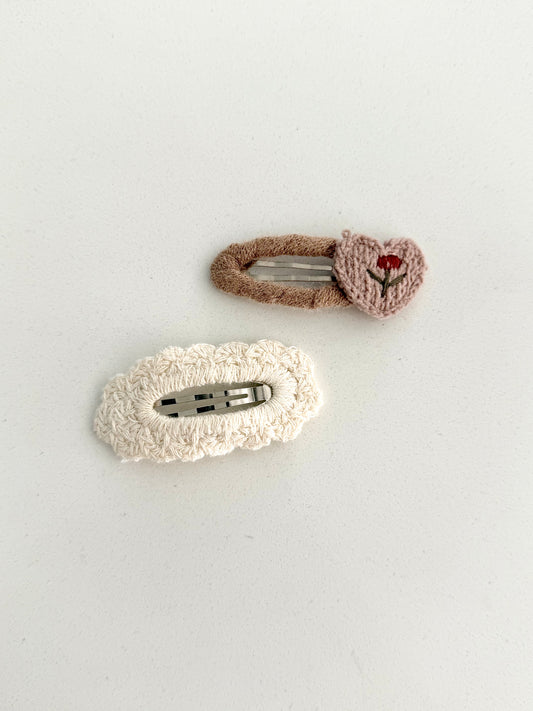 Soft knitted hair clips – beige embroidered flower barrette and cream textured clip on white background.