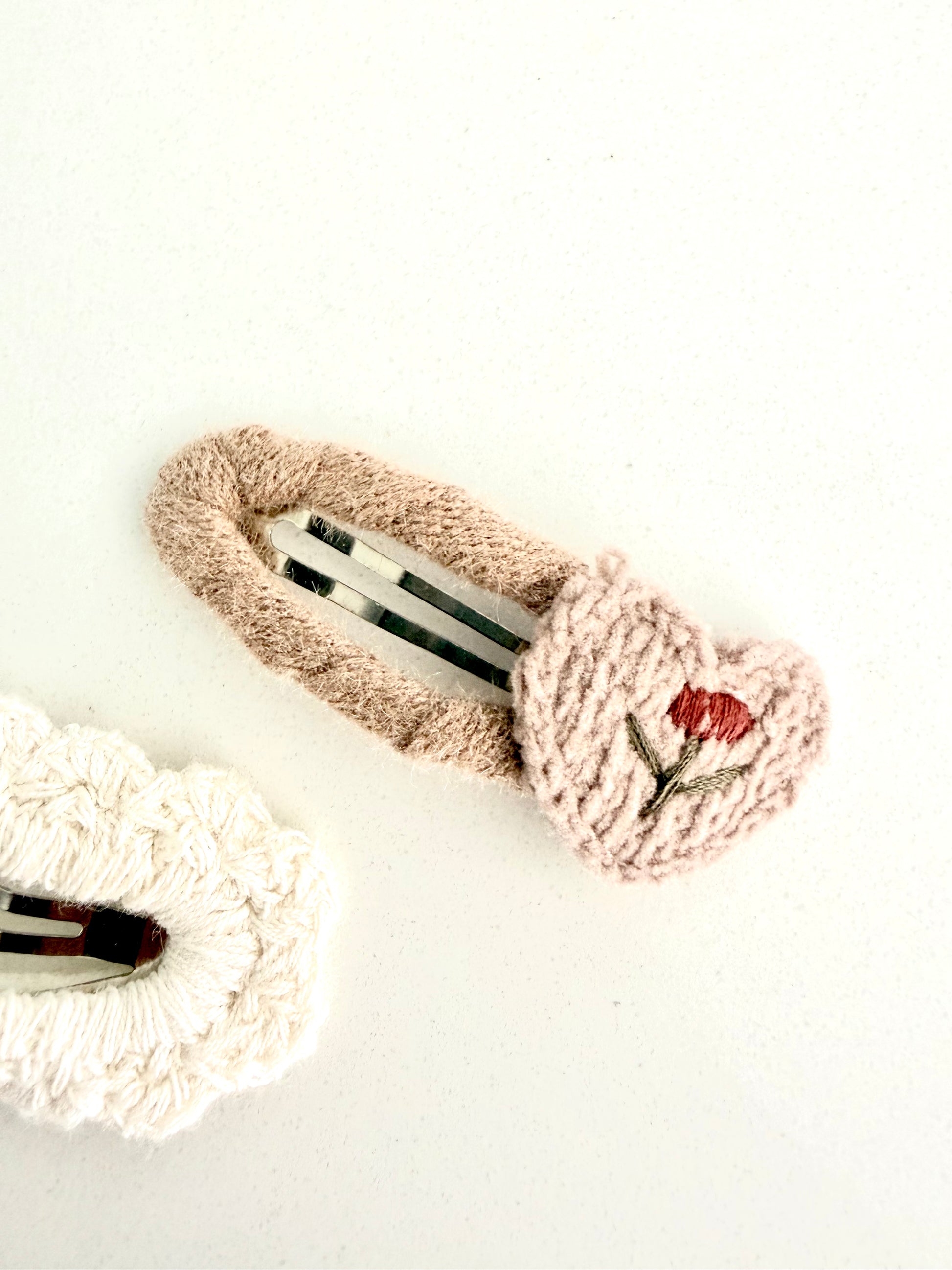 Soft knitted hair clips – beige embroidered flower barrette and cream textured clip on white background.