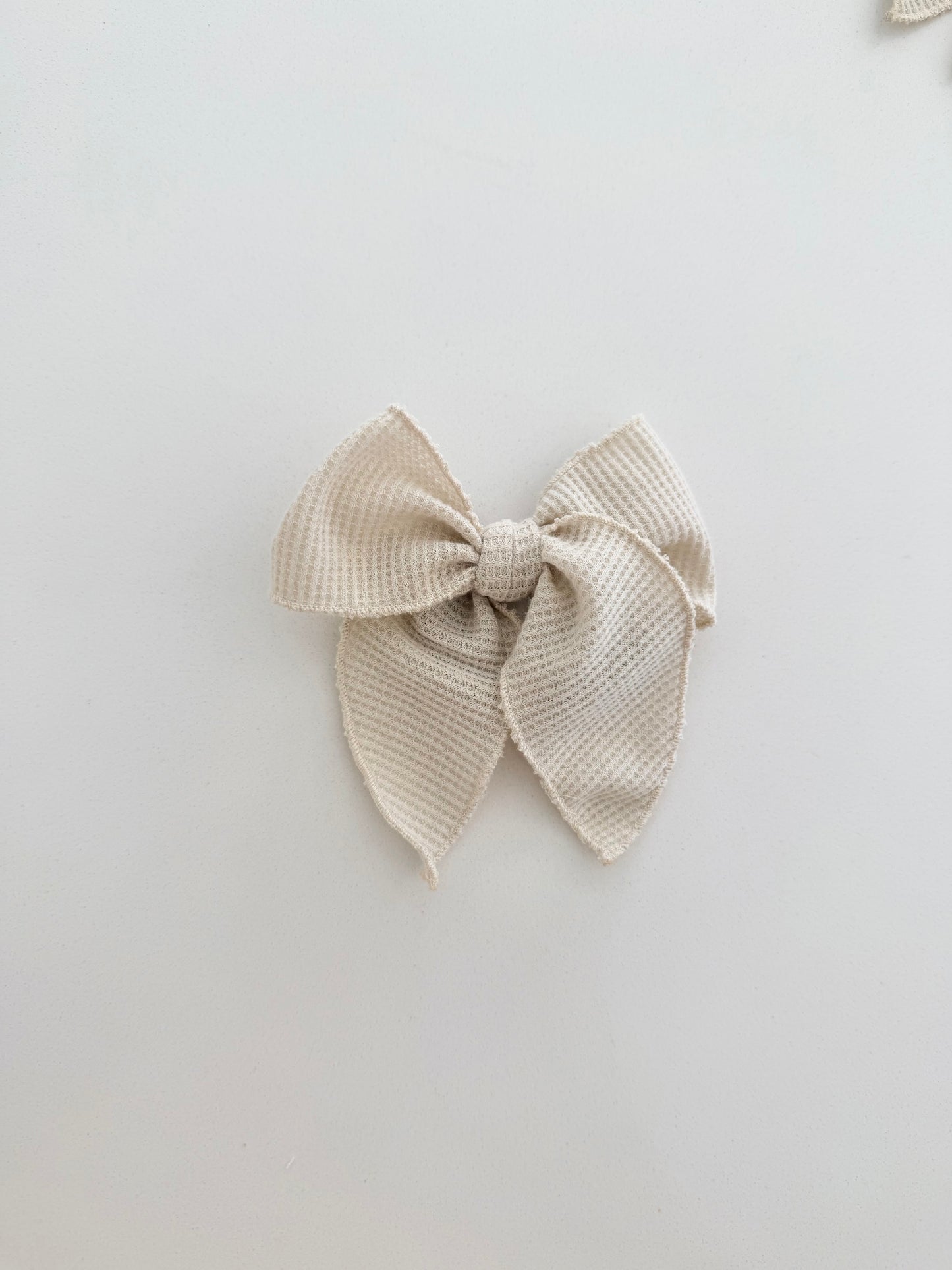 Mini fable Beige textured waffle bow on a light gray background