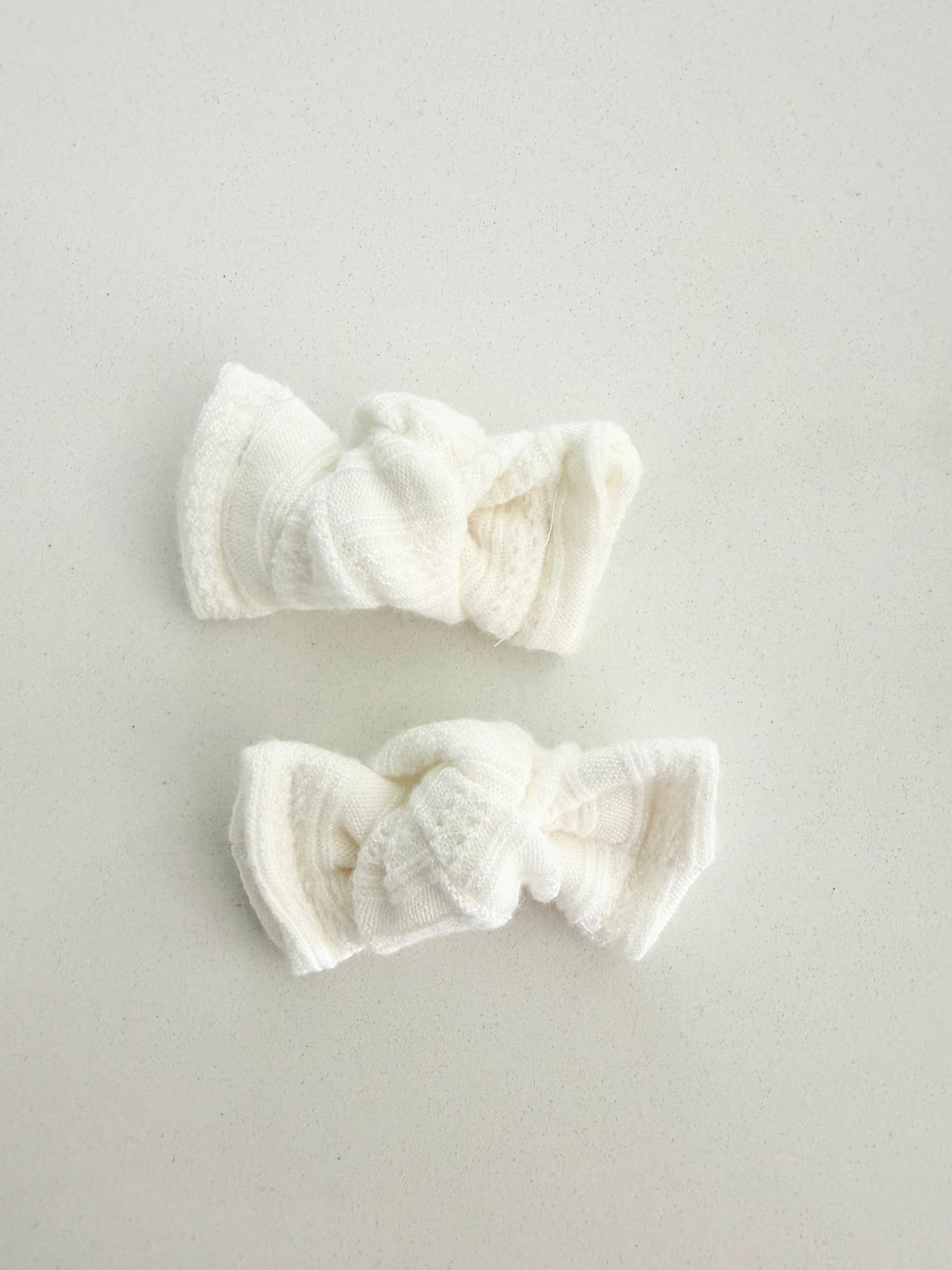 Ivory knit toddler pigtail bows, handmade in two sizes for a soft, cozy, and classic everyday look.