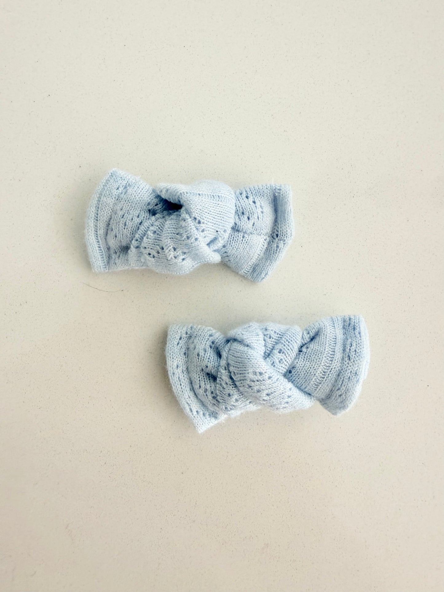 Baby blue knit pigtail bows for toddlers, handmade in two sizes for a soft and cozy everyday look.