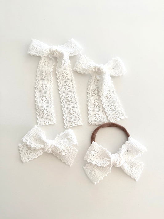 Ivory lace school girl bow on alligator clip and nylon headband, displayed for newborns, babies, and girls.