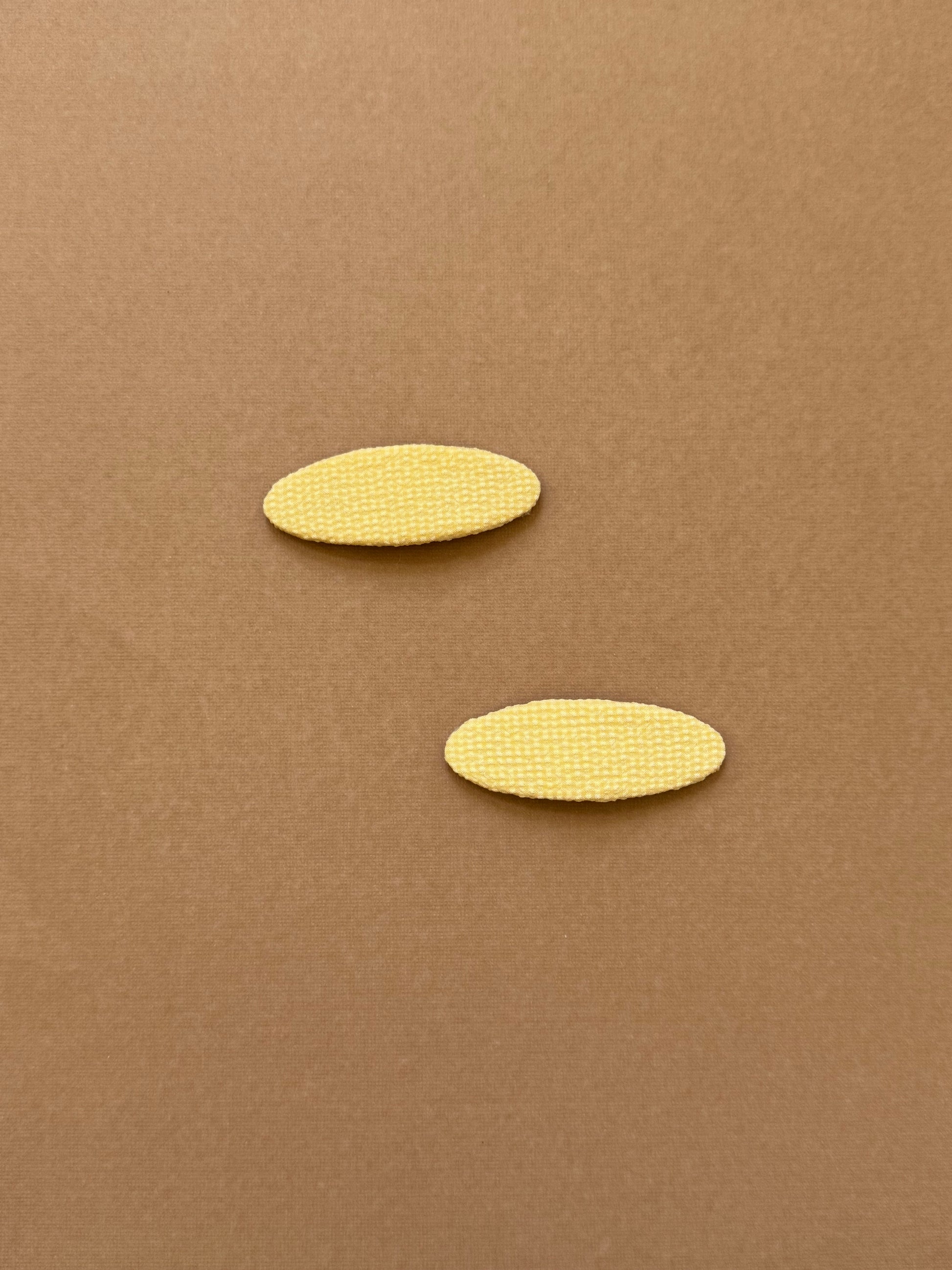 Oval yellow snap clip made with textured fabric