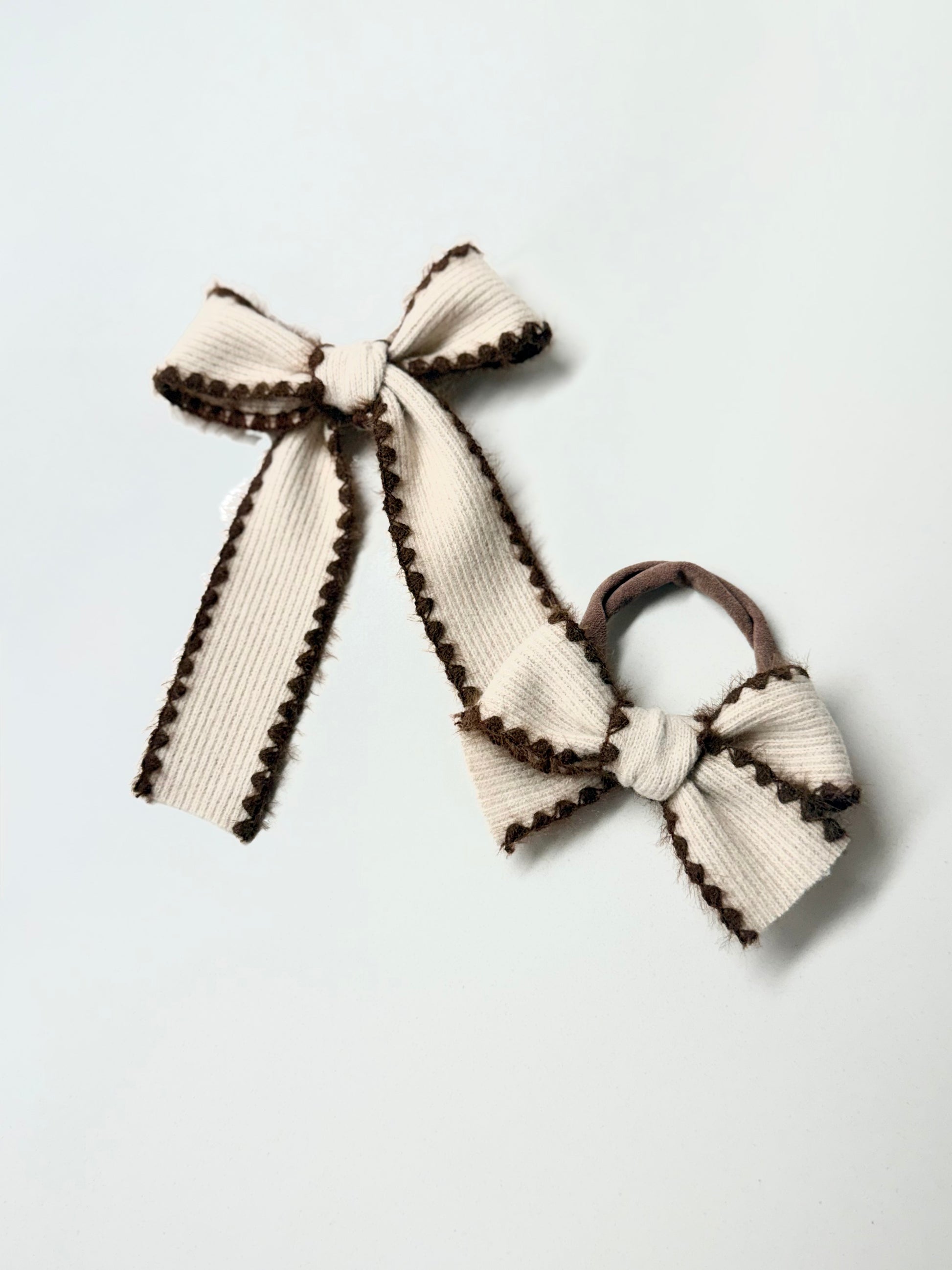 Two cream-colored hair bows with brown trim 