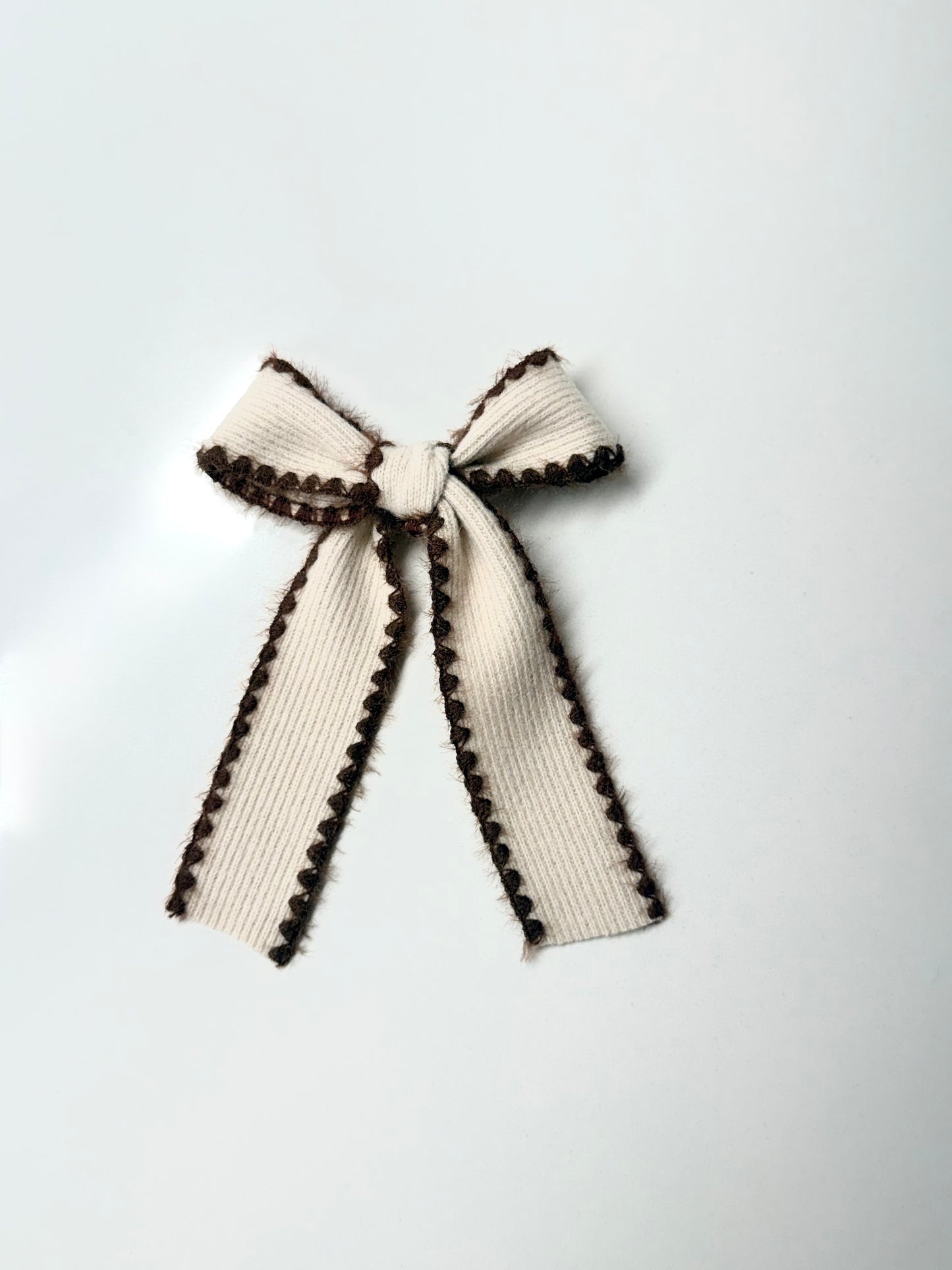 Cream knit hair bow with cocoa brown stitched trim, handmade accessory for babies, toddlers, and girls.