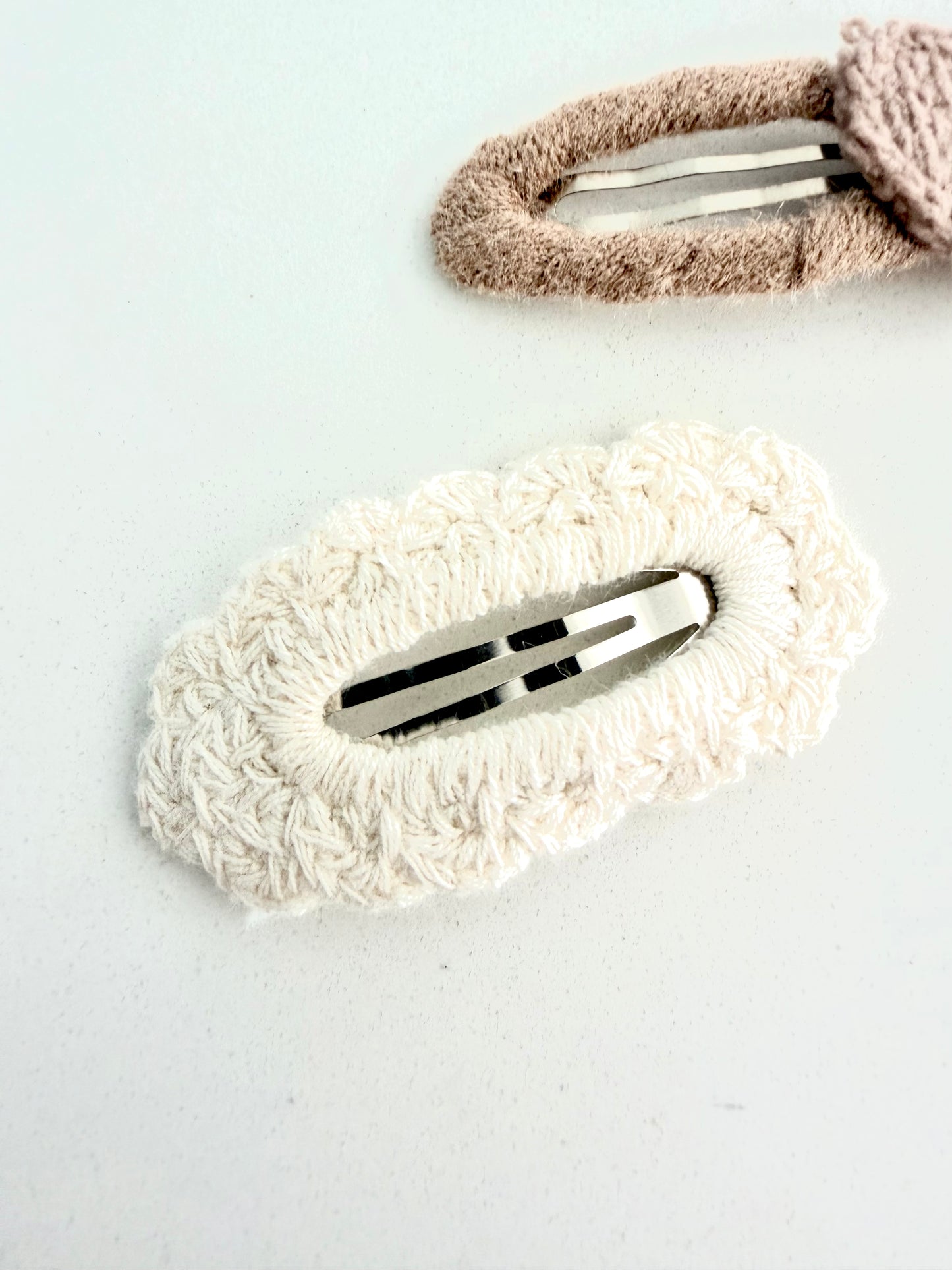 Soft knitted hair clips – beige embroidered flower barrette and cream textured clip on white background.