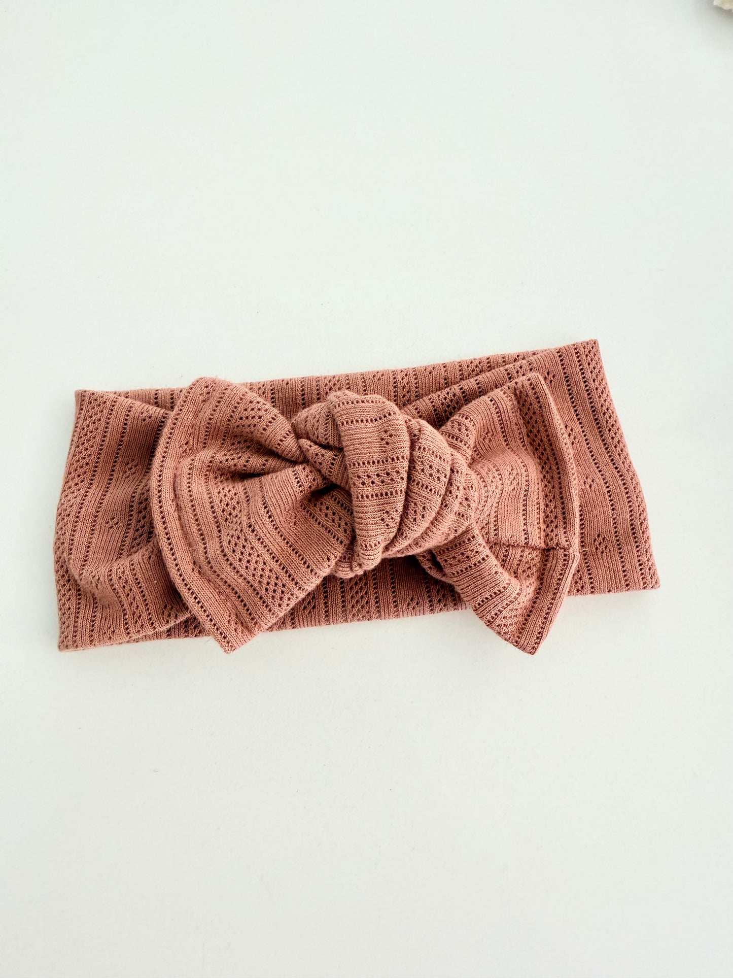 Knitted headband with a large bow on a light background