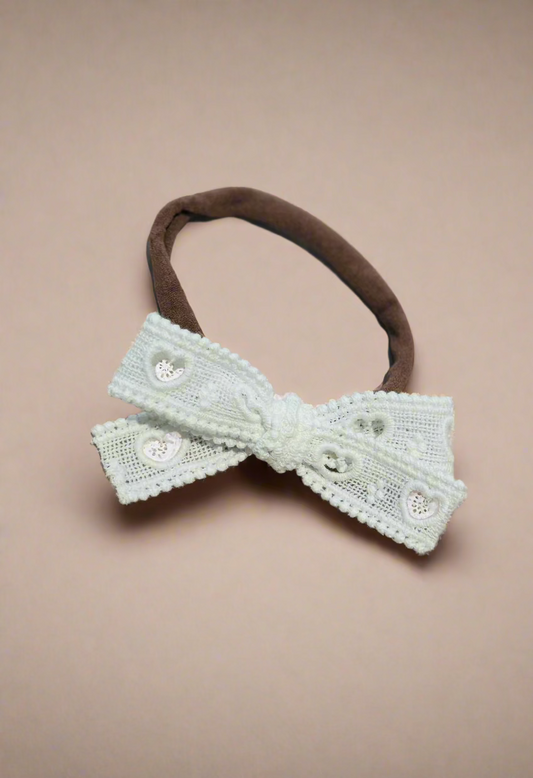 heart eyelet bow with pompom detail 